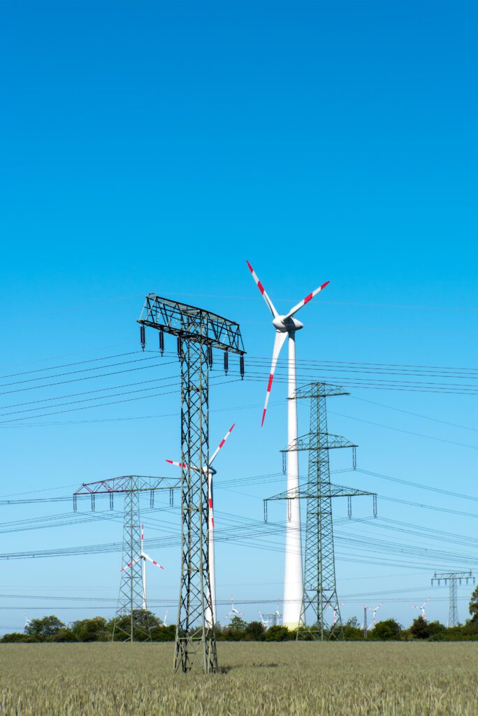 Wind turbines and power transmission towers in a cultivated field.