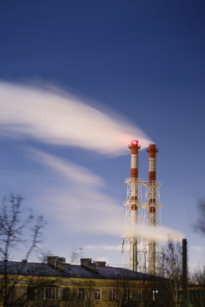 Red and white smokestacks emitting steam against a night sky.