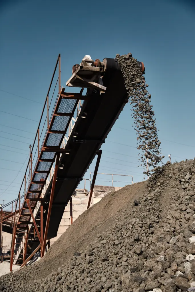 Conveyor belt dumping gravel into a large pile.